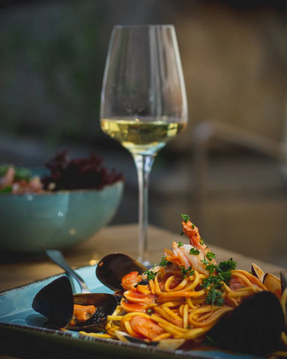 Accord entre un plat de pâtes aux fruits de mer et un verre de vin blanc